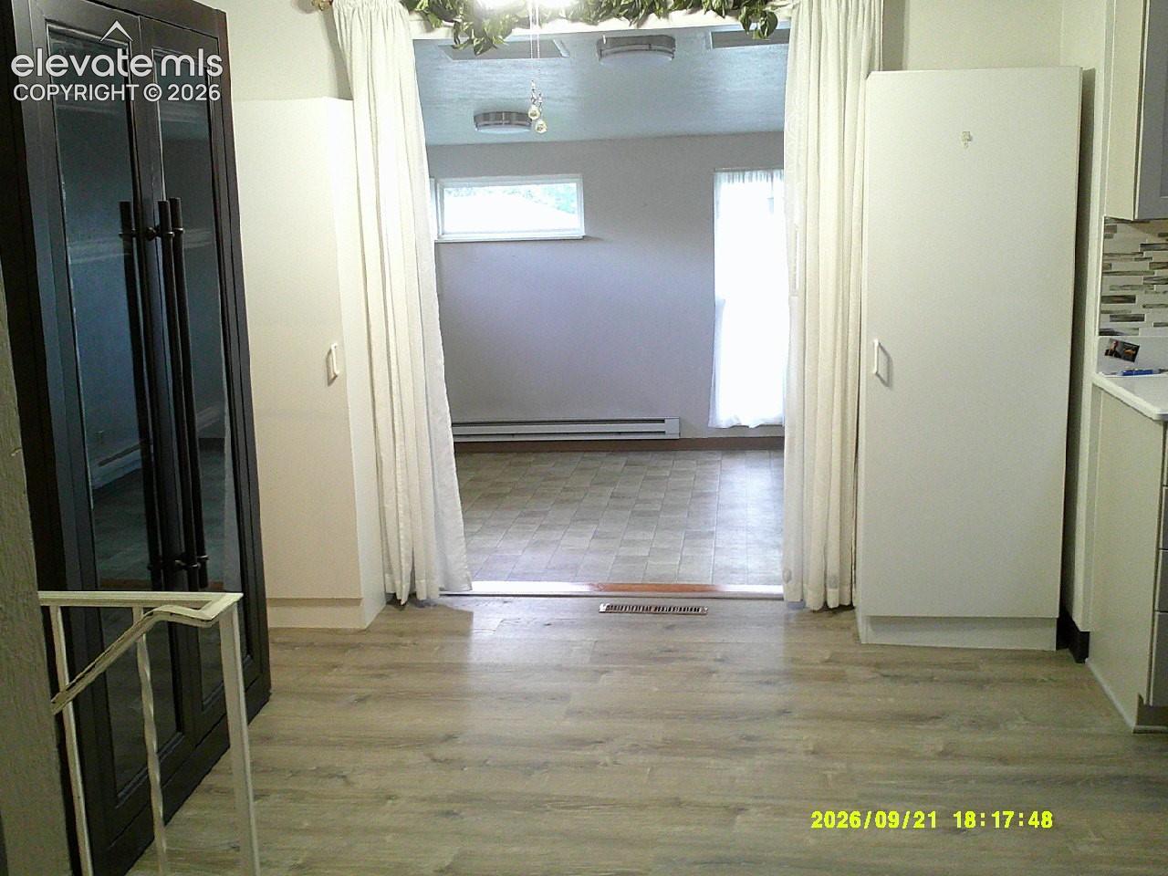 Wood-finish flooring leading to an additional space with tile flooring