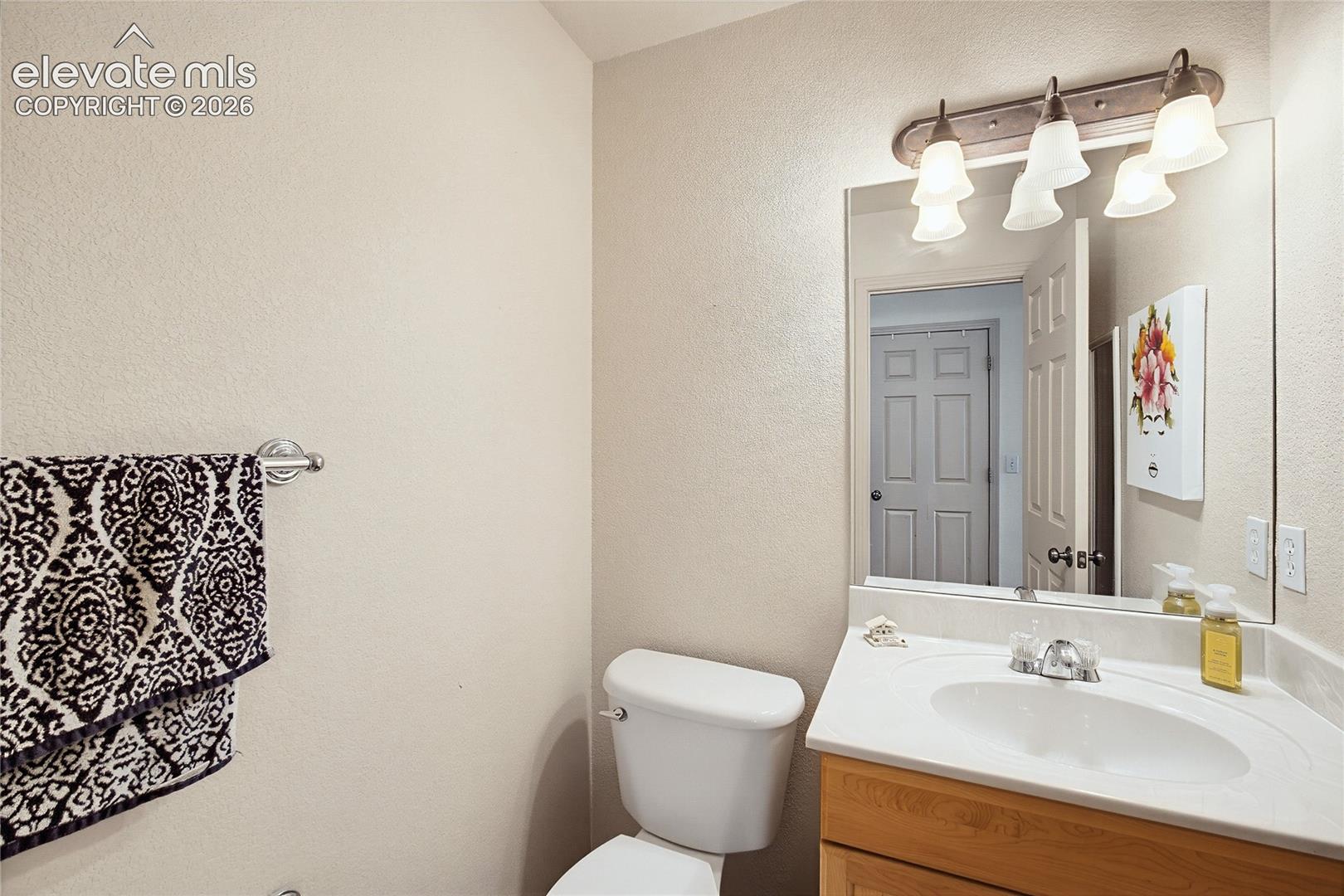 Compact vanity with integrated sink, chrome faucet, and wood-finish cabinetry