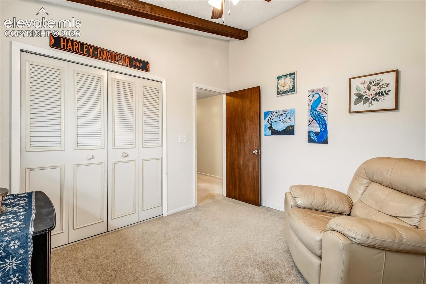 Exposed wooden ceiling beam, carpeted flooring, white louvered-panel closet doors, and a solid wood interior door