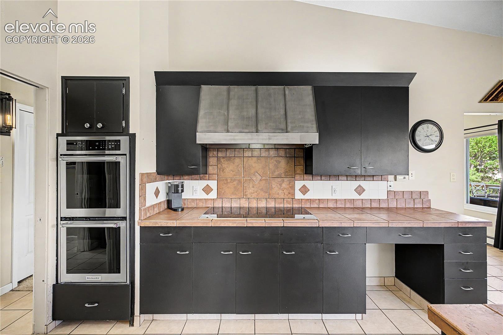 A tile backsplash and a built-in copper range hood pair with modern stainless appliances, blend vintage charm with modern convenience.