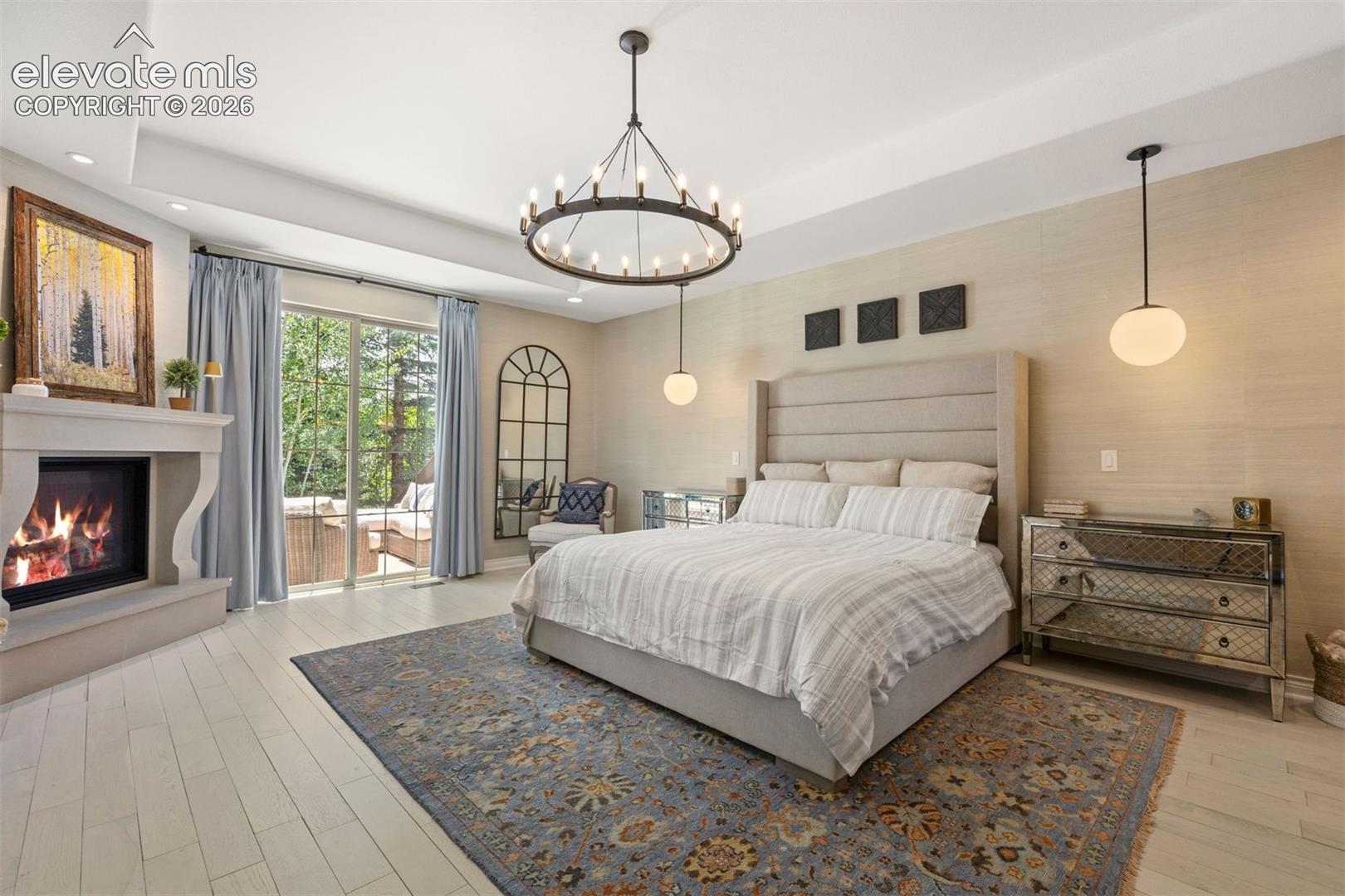 Spacious room featuring light wood-finish flooring, a stone-surround fireplace, and a sliding glass door opening to an outdoor area