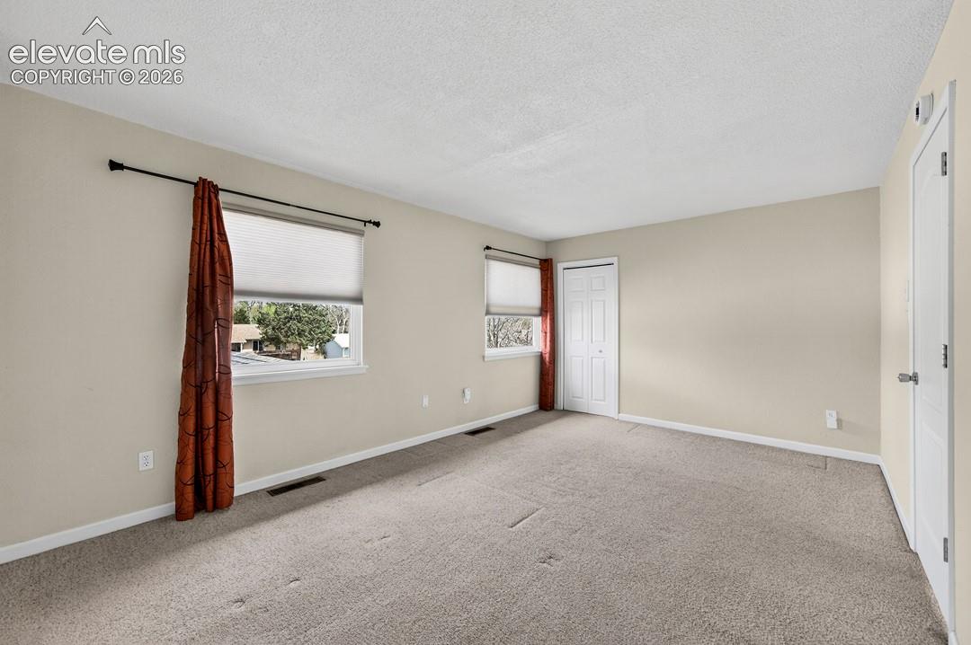 Neutral wall tones, two windows with roller shades, and light-colored carpeting