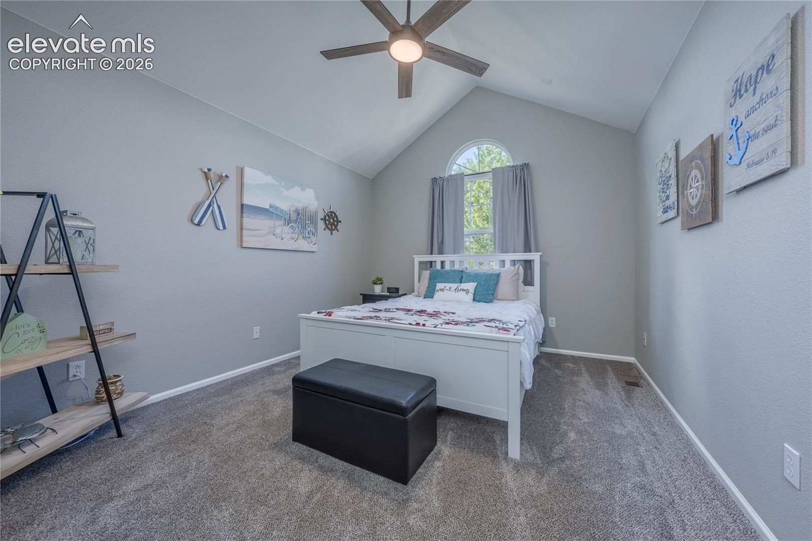 Vaulted ceiling featuring a central ceiling fan with an integrated light fixture, arched window, and neutral wall tones