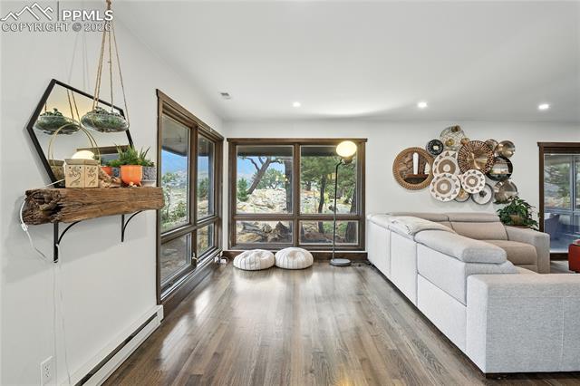 Living room with a baseboard heating unit, wood finished floors, and recessed lighting
