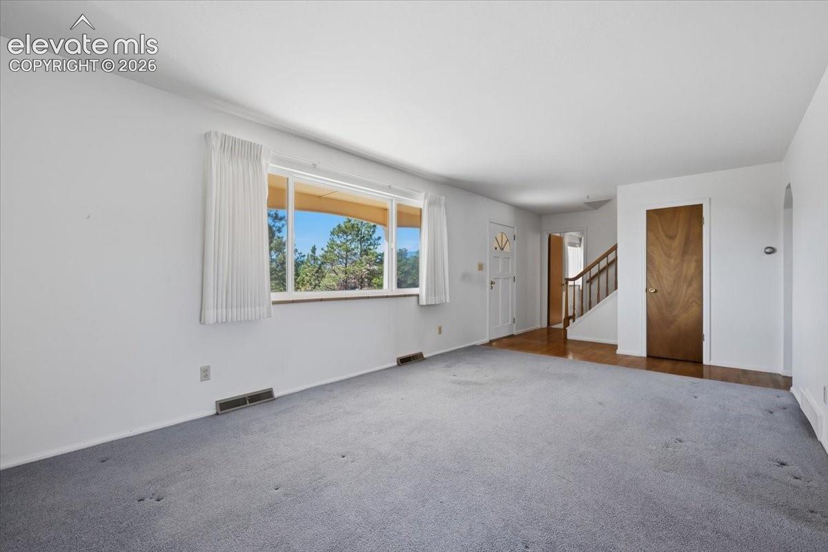 Interior space featuring large picture windows, wood-finish flooring, a multi-lite exterior entry door, and a wooden staircase with a handrail