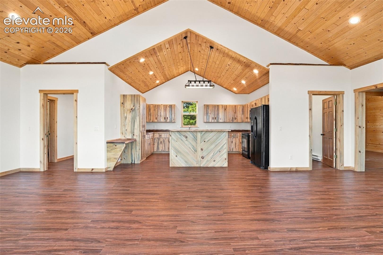 Vaulted ceiling with exposed wood planking, wood-finish flooring, custom wood cabinetry, central island, and recessed lighting