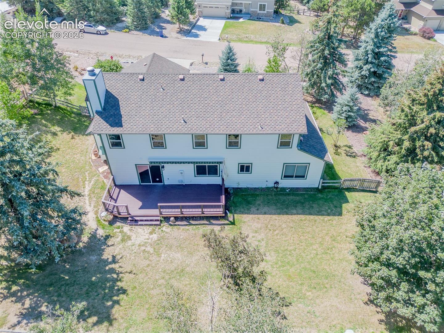 Two-story residence featuring a shingled roof, exterior chimney, and multiple windows