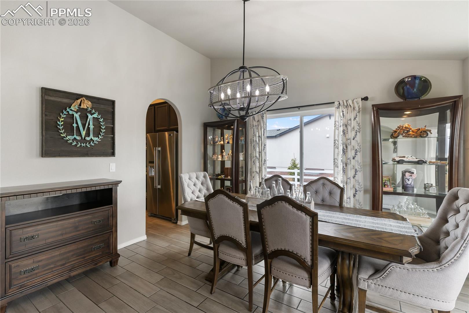 Spacious dining area featuring an arched doorway and a contemporary chandelier