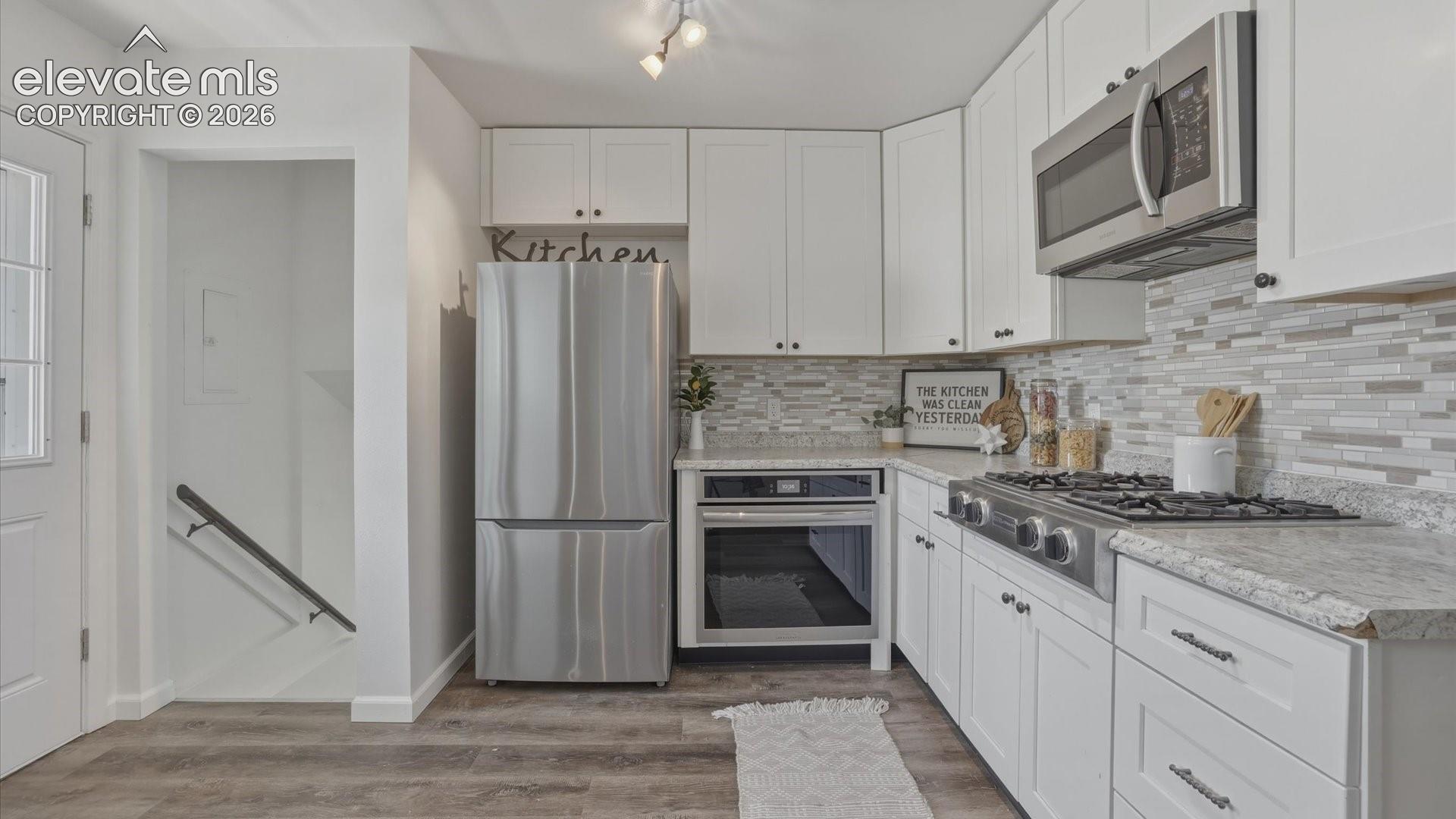 The updated Kitchen boasts white cabinetry, granite countertops, tile backsplash, and stainless appliances.
