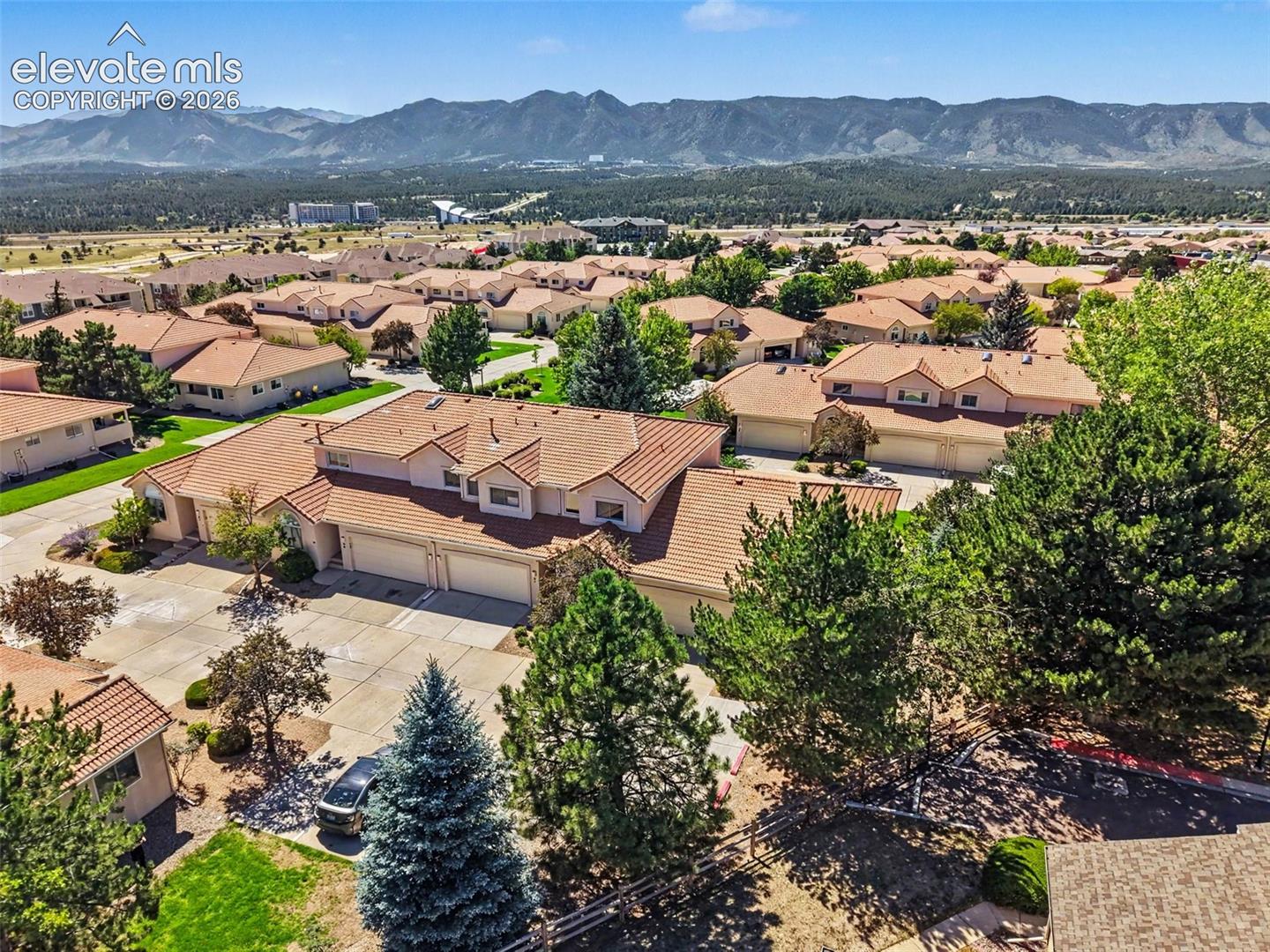 Tile roofing and mature landscaping define this residential community, set against a distant mountain range