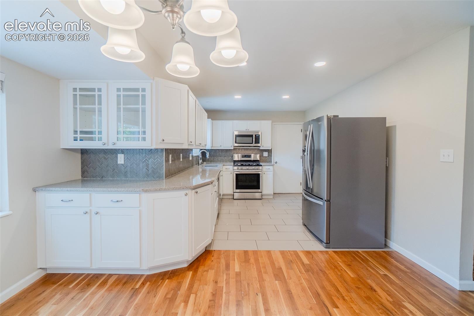 Kitchen featuring white cabinetry, light-toned countertops, a full stainless steel appliance suite, and a tiled backsplash