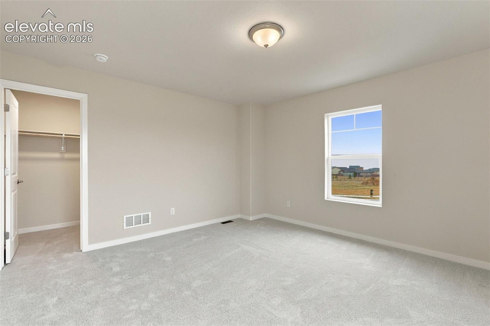 Neutral interior room featuring plush carpeting, a single-light ceiling fixture, and a window with a transom pane