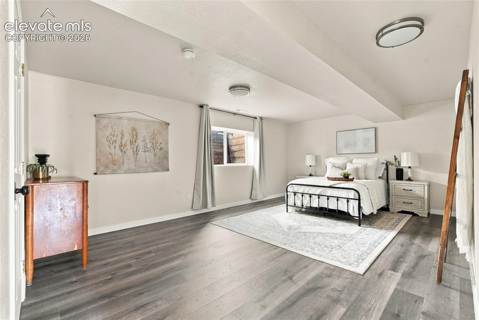 Basement room featuring wood-finish flooring, recessed lighting, and a window with privacy curtains