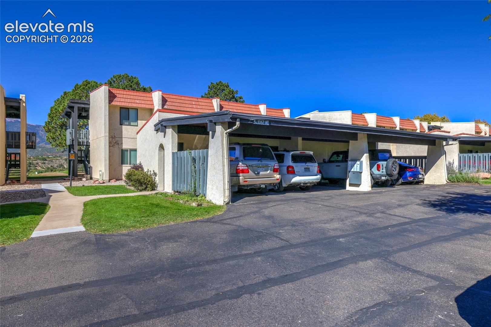 Stucco exterior featuring a terracotta-tiled roof and a covered carport and storage closet