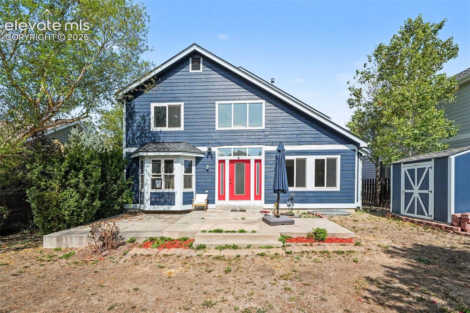Blue siding exterior with a prominent red entry door, a bay window on the left, and multiple large windows