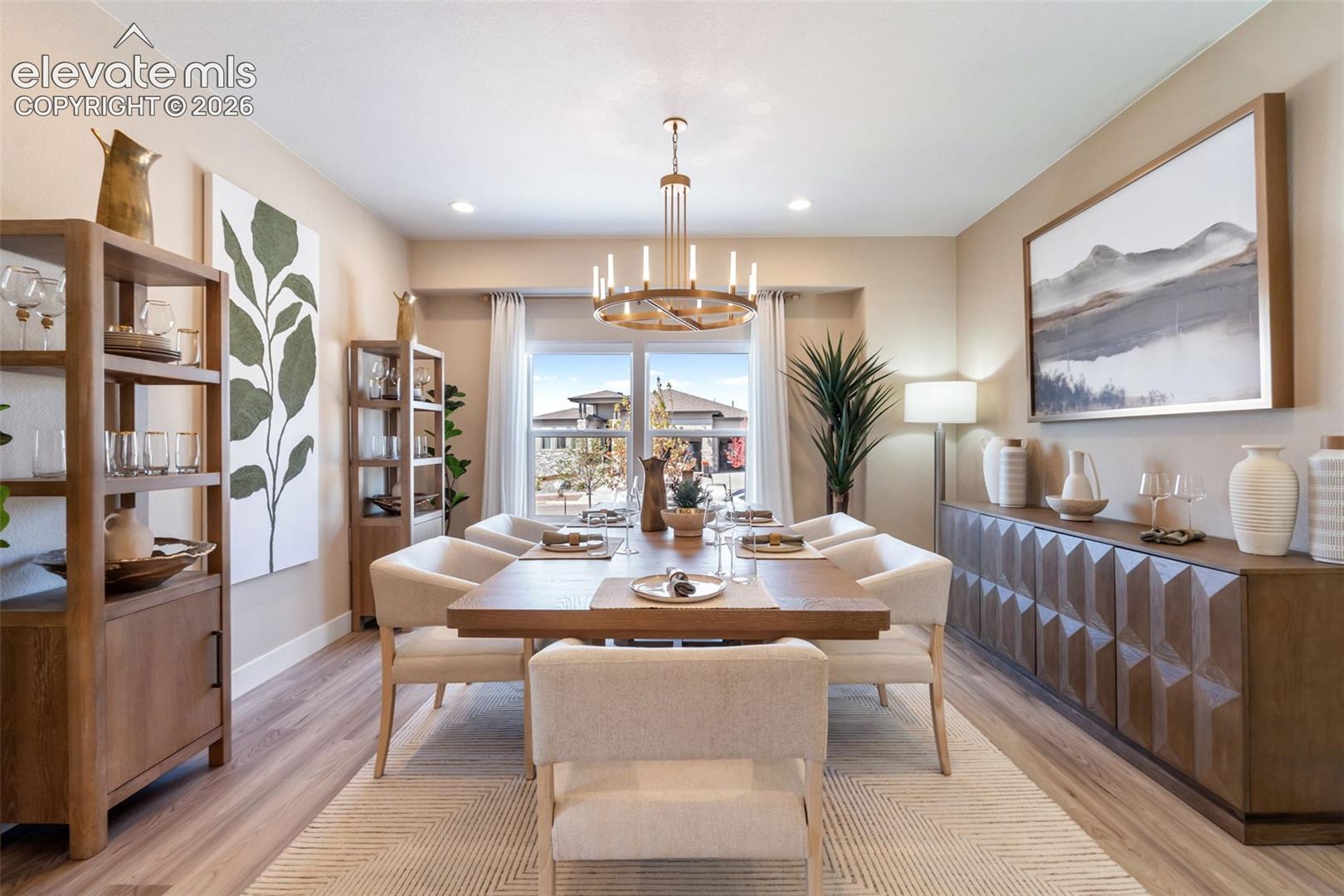 Dining space featuring wood-finish flooring, a tiered circular chandelier, recessed lighting, and a large window