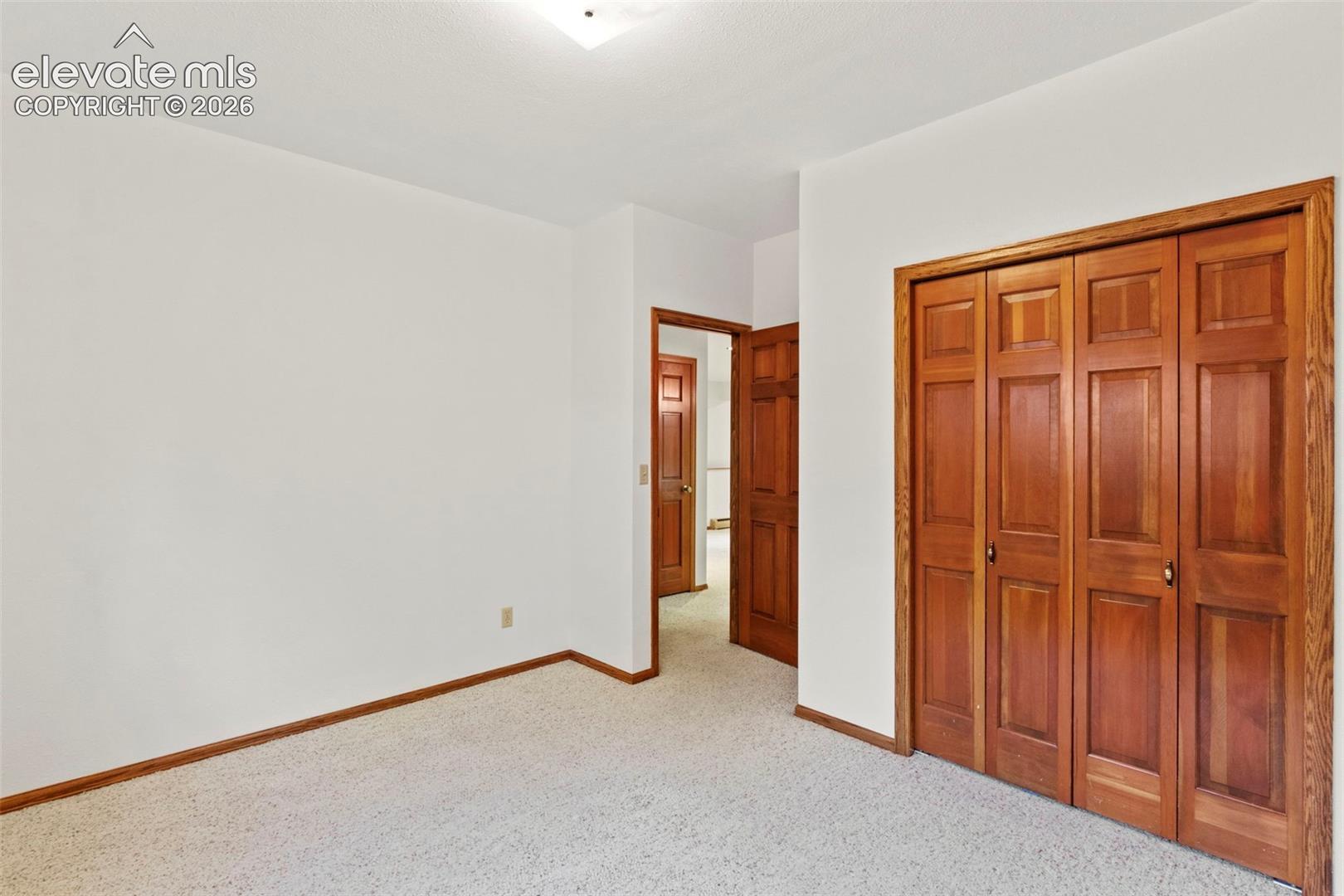 Neutral-toned carpeting, wood-finish interior doors with six-panel detailing, and white walls