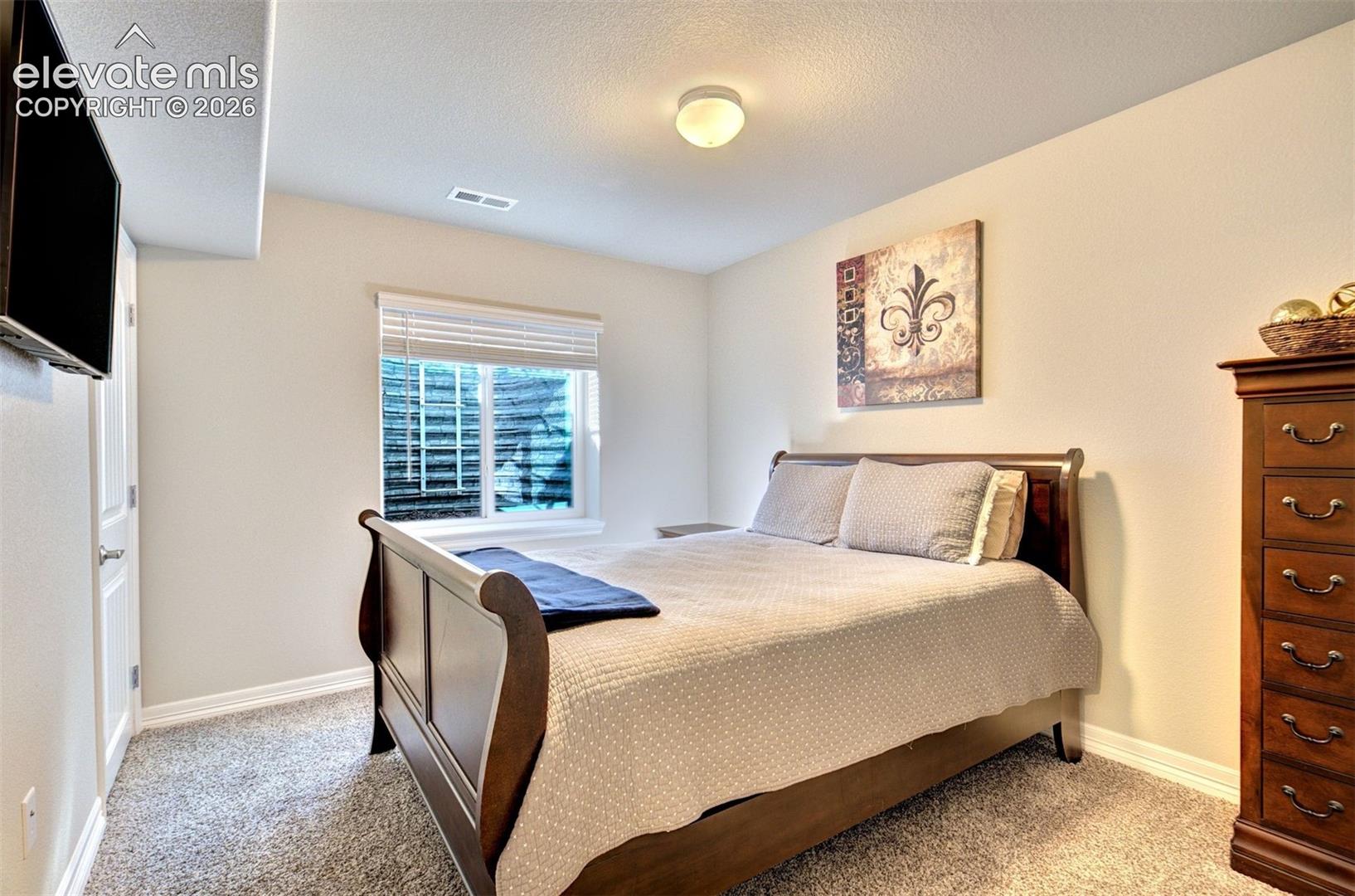 Neutral wall coloring, carpeted flooring, window with integrated blinds, and flush-mount ceiling lighting