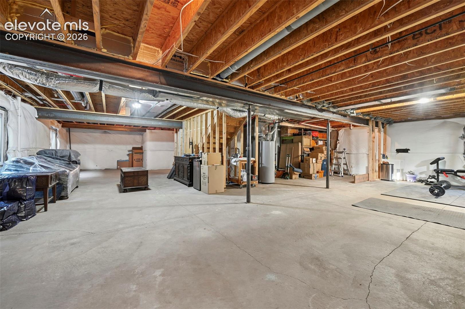 Unfinished basement featuring exposed wood joists, concrete flooring, and structural support beams