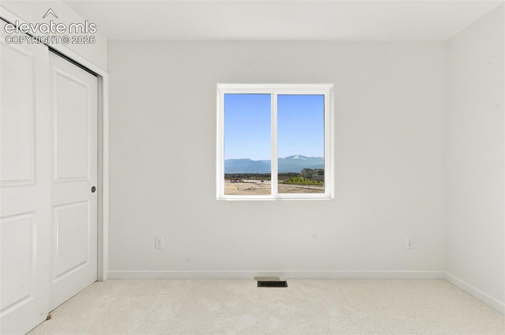 White walls, light-toned carpet, and a window with mountain scenery