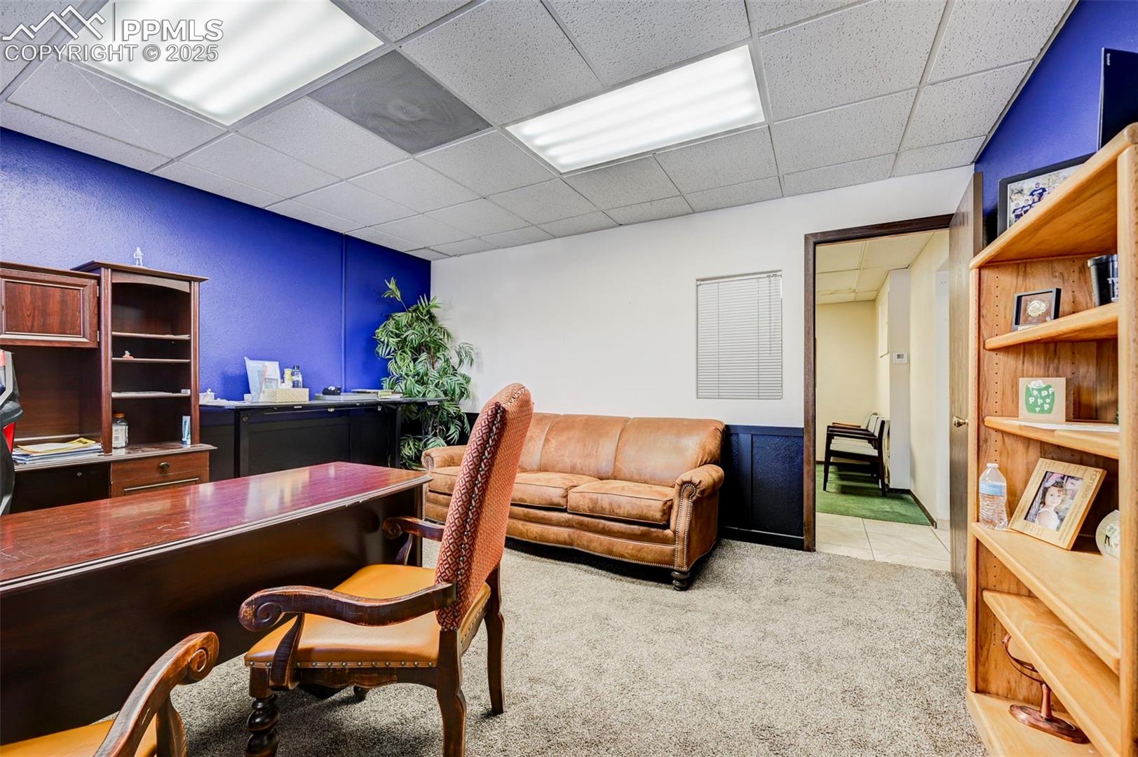 Office with a paneled ceiling and carpet
