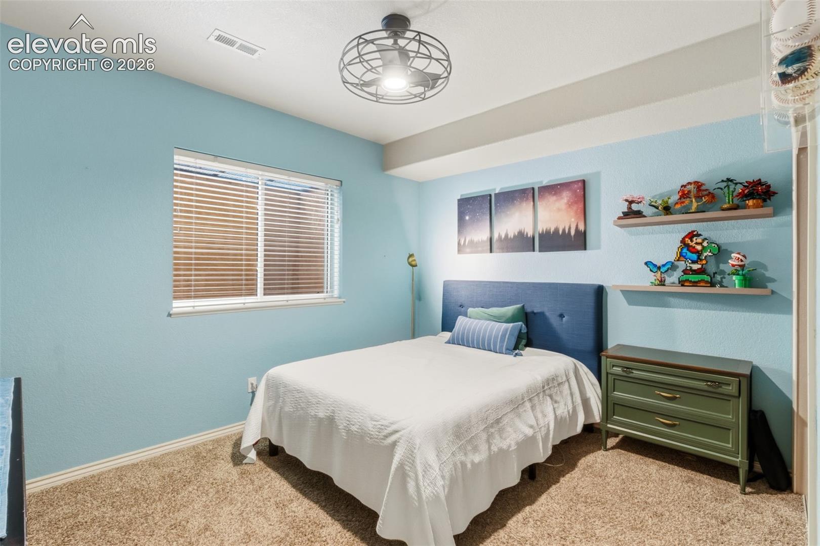 Bedroom featuring textured blue walls, light-toned carpeting, and a white ceiling
