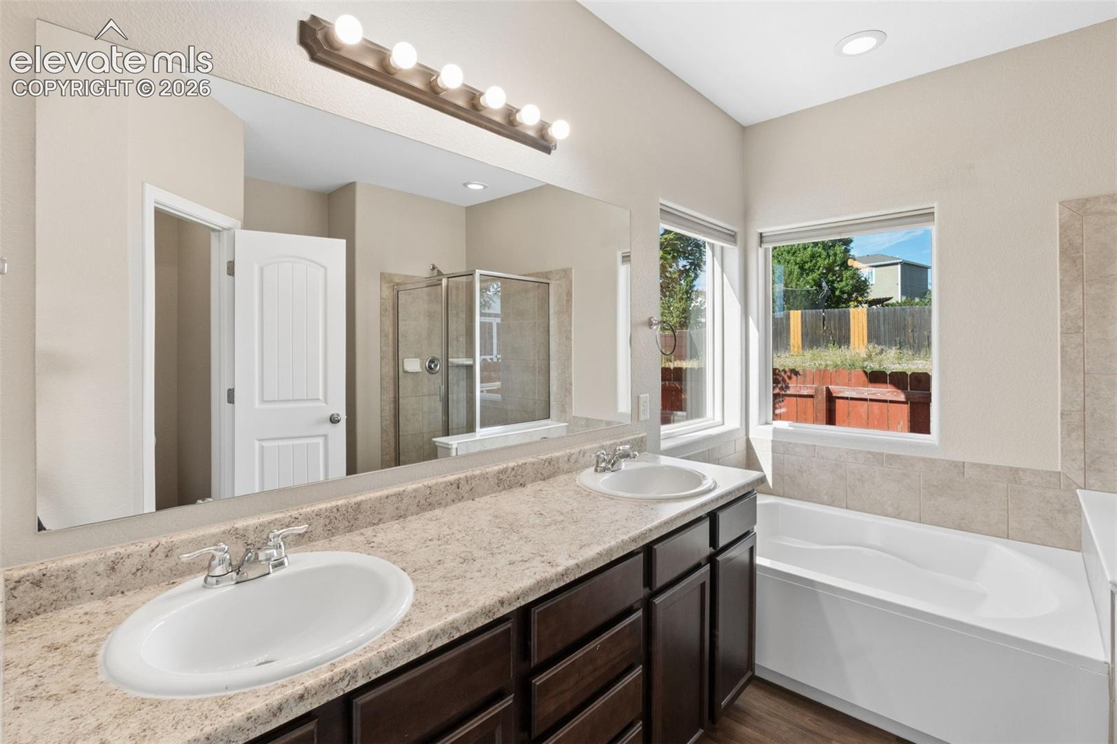 Dual vanity with undermount sinks, speckled countertop, and dark wood-finish cabinetry