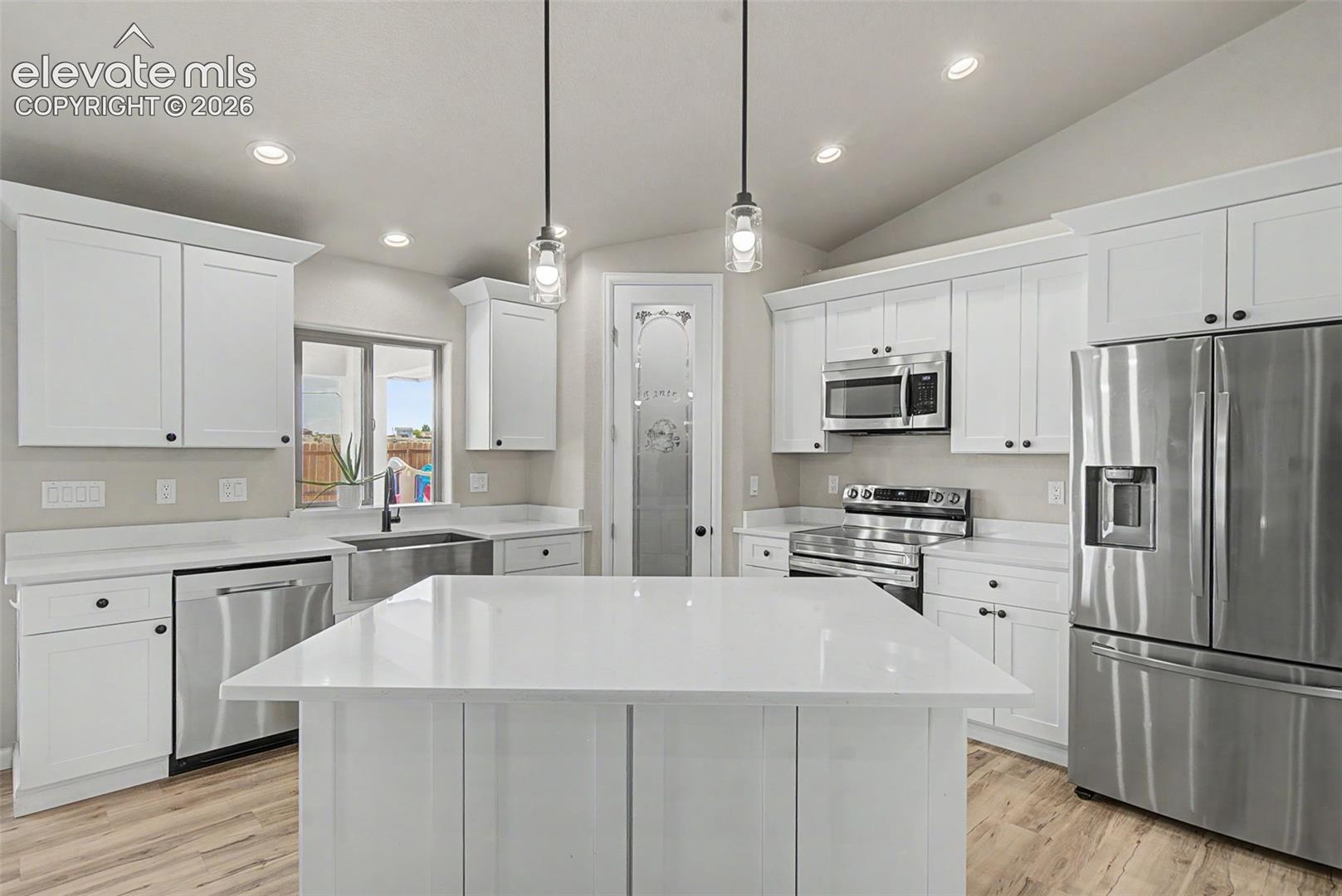 Kitchen featuring white cabinetry, stainless steel appliances, a center island with a solid surface countertop, wood-finish flooring, and recessed lighting