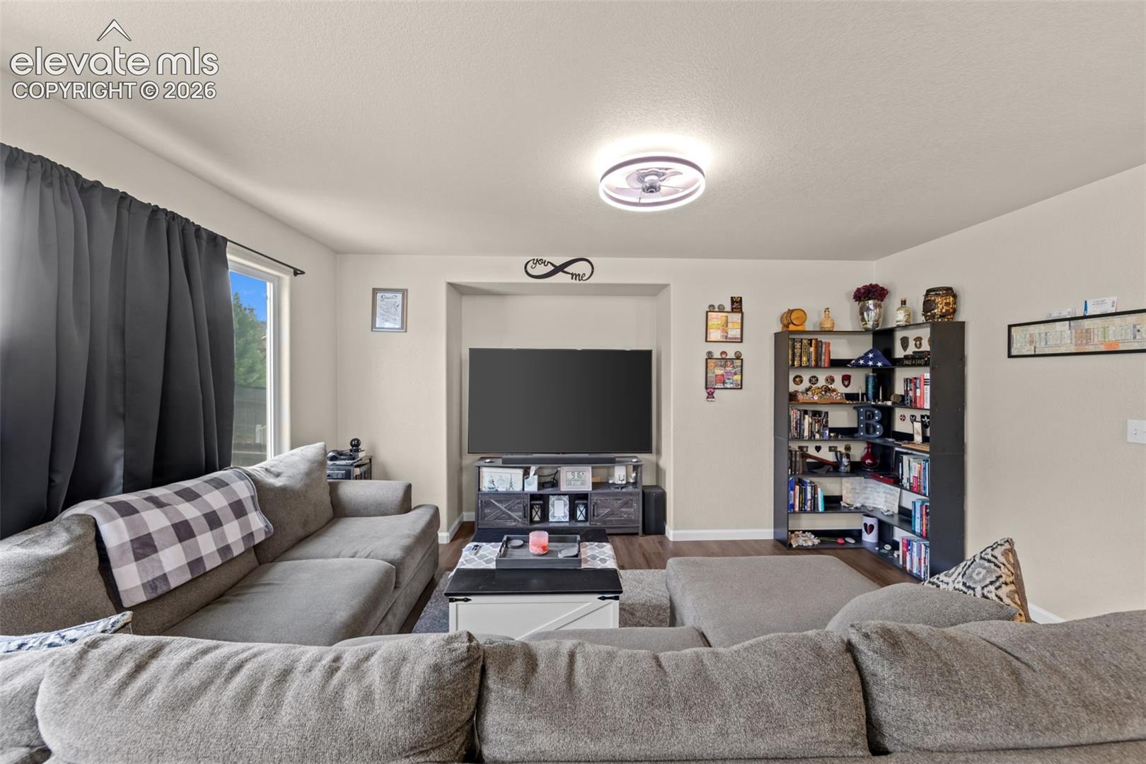 Recessed media niche, modern ceiling light fixture, neutral wall color, wood-finish flooring, and a large window