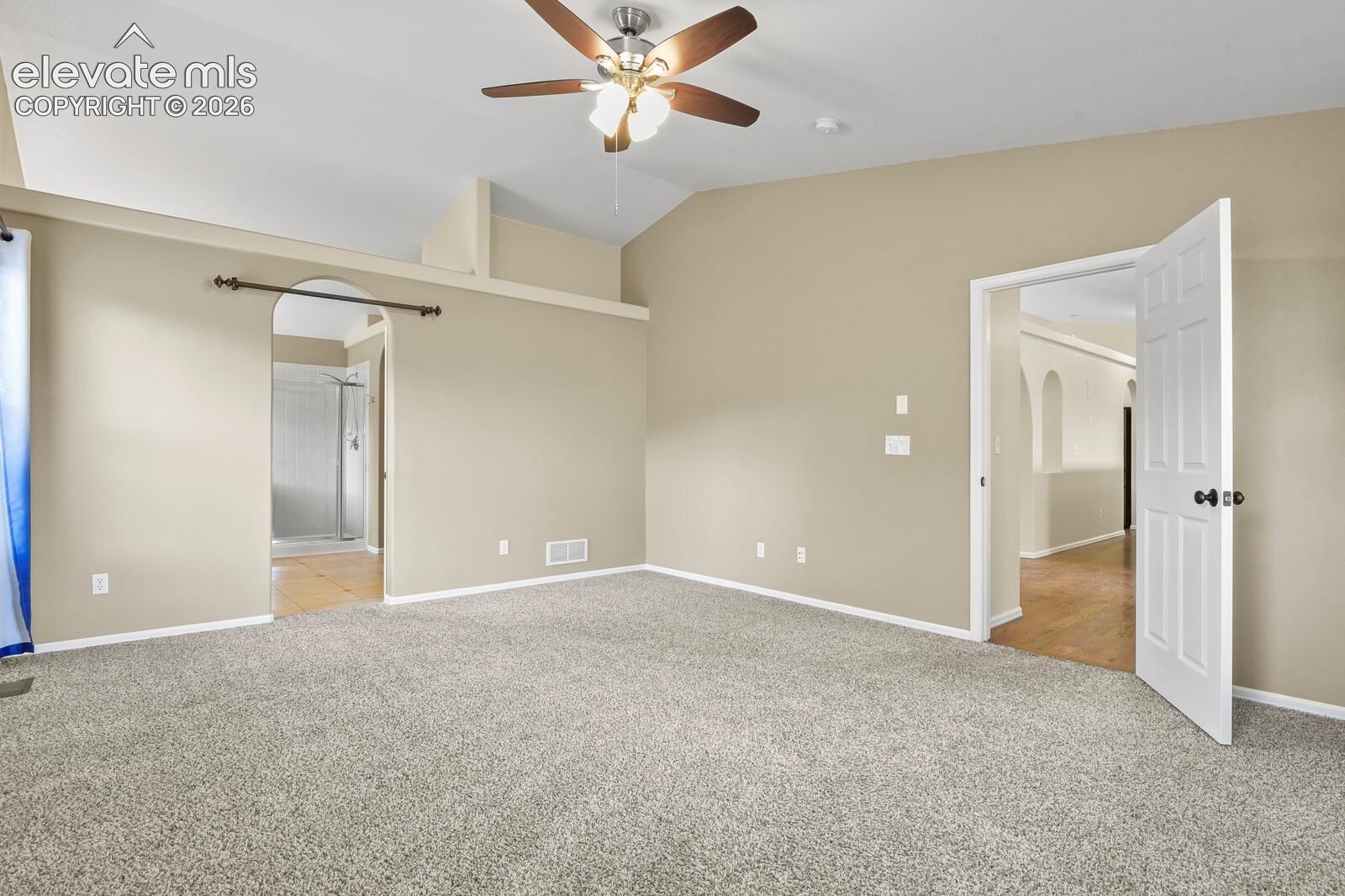 Spacious room featuring vaulted ceilings, Ceiling Fan and neutral-toned walls