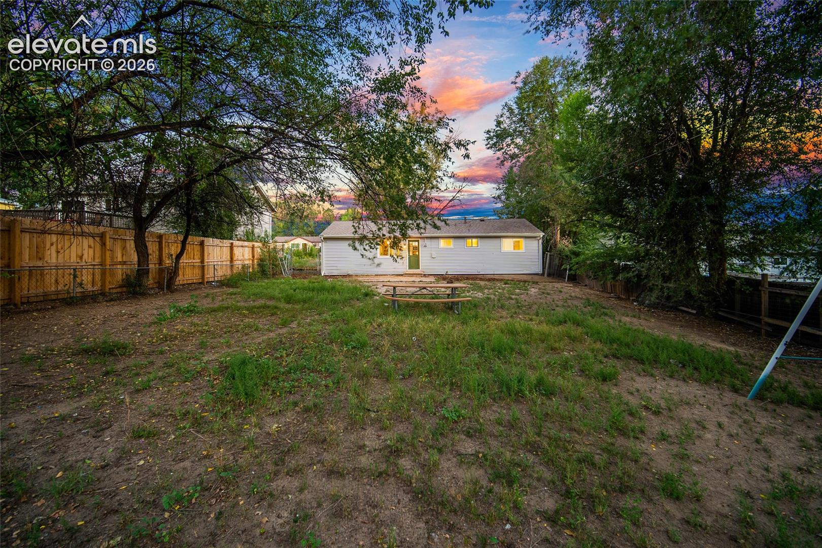 Expansive rear yard featuring mature trees and a wood privacy fence