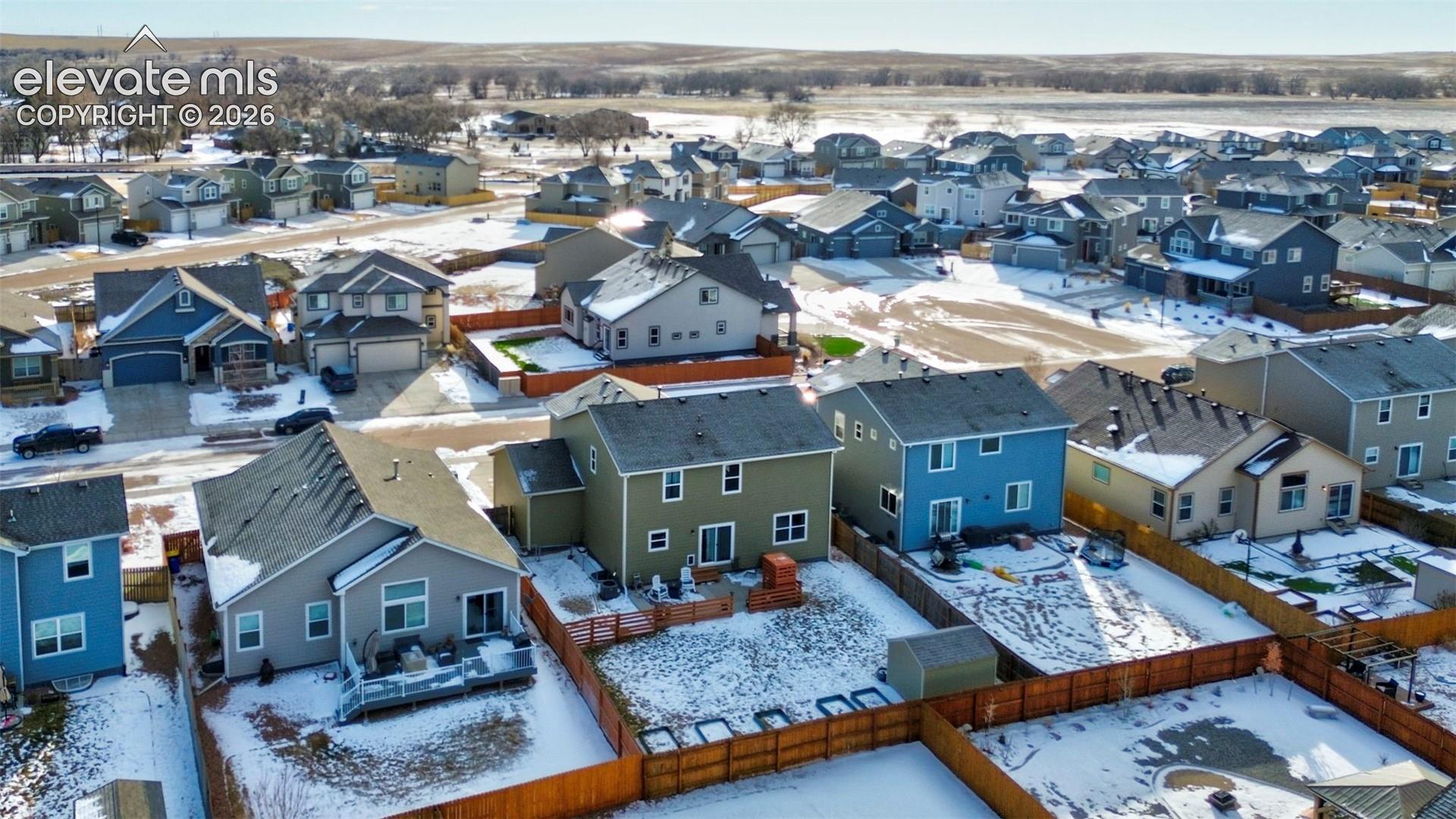 Aerial perspective of a residential neighborhood featuring multi-story dwellings, fenced backyards, and paved street infrastructure