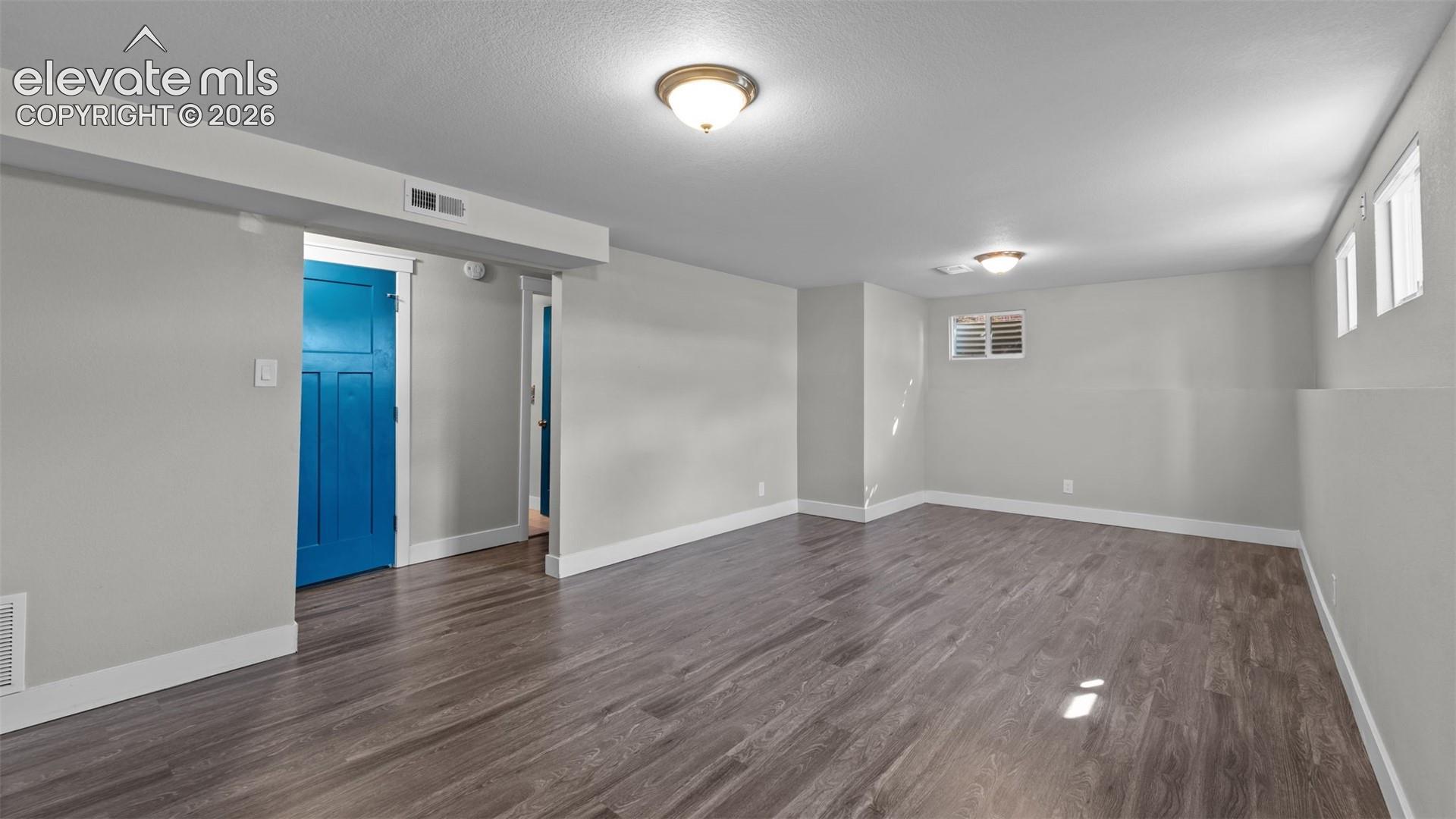 Spacious room featuring wood-finish flooring, light gray walls, white trim, and recessed lighting