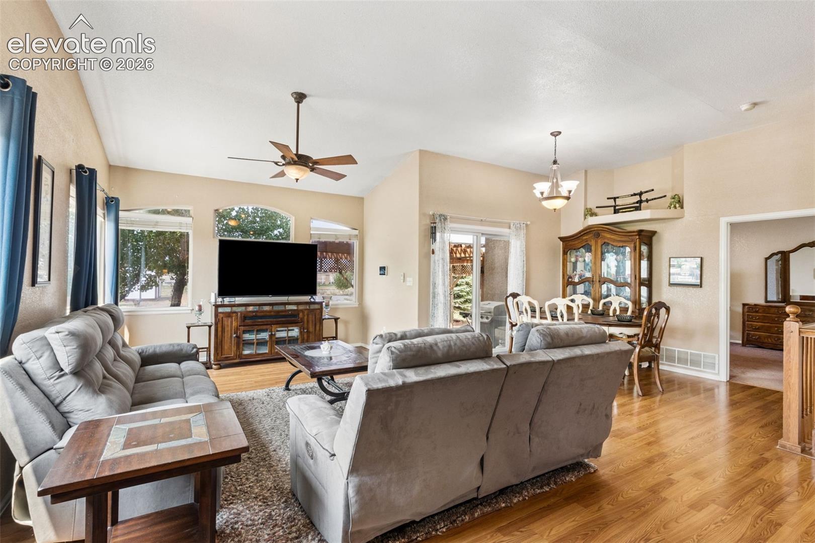Vaulted ceilings, wood-finish flooring, arched windows, and integrated ceiling fan and lighting fixtures