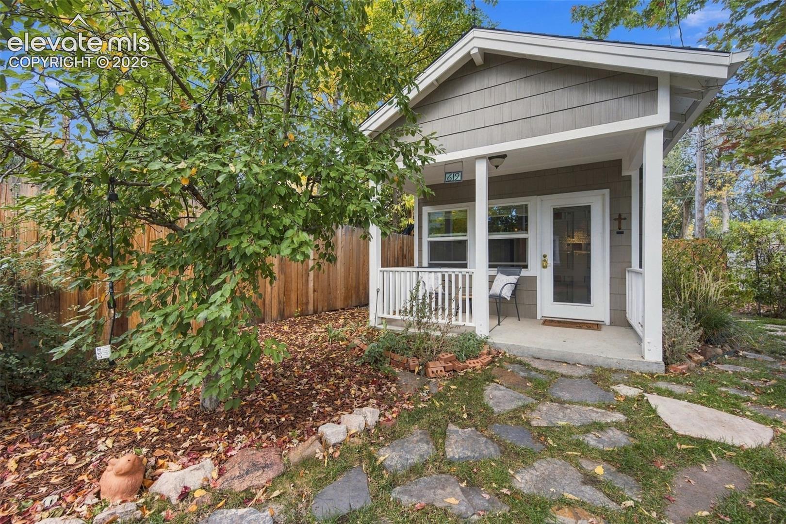 Gabled cottage exterior featuring horizontal lap siding, a covered front porch with white railings, and a flagstone walkway