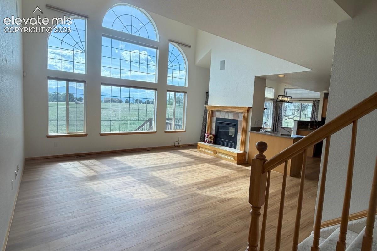 Soaring ceilings with arch-top windows, wood-finish flooring, and a fireplace with a wood mantle. No staging.