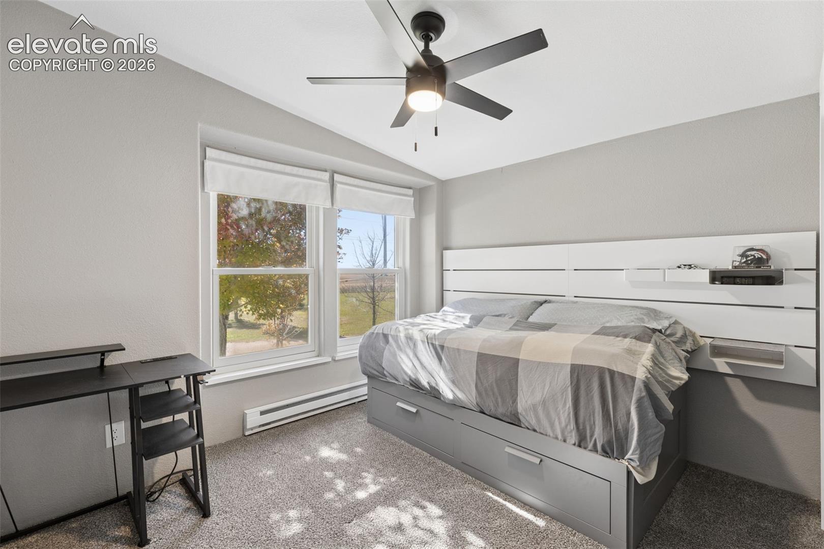 Room featuring carpeted flooring, a ceiling fan with integrated lighting, dual pane windows, and a built-in horizontal slat wall panel