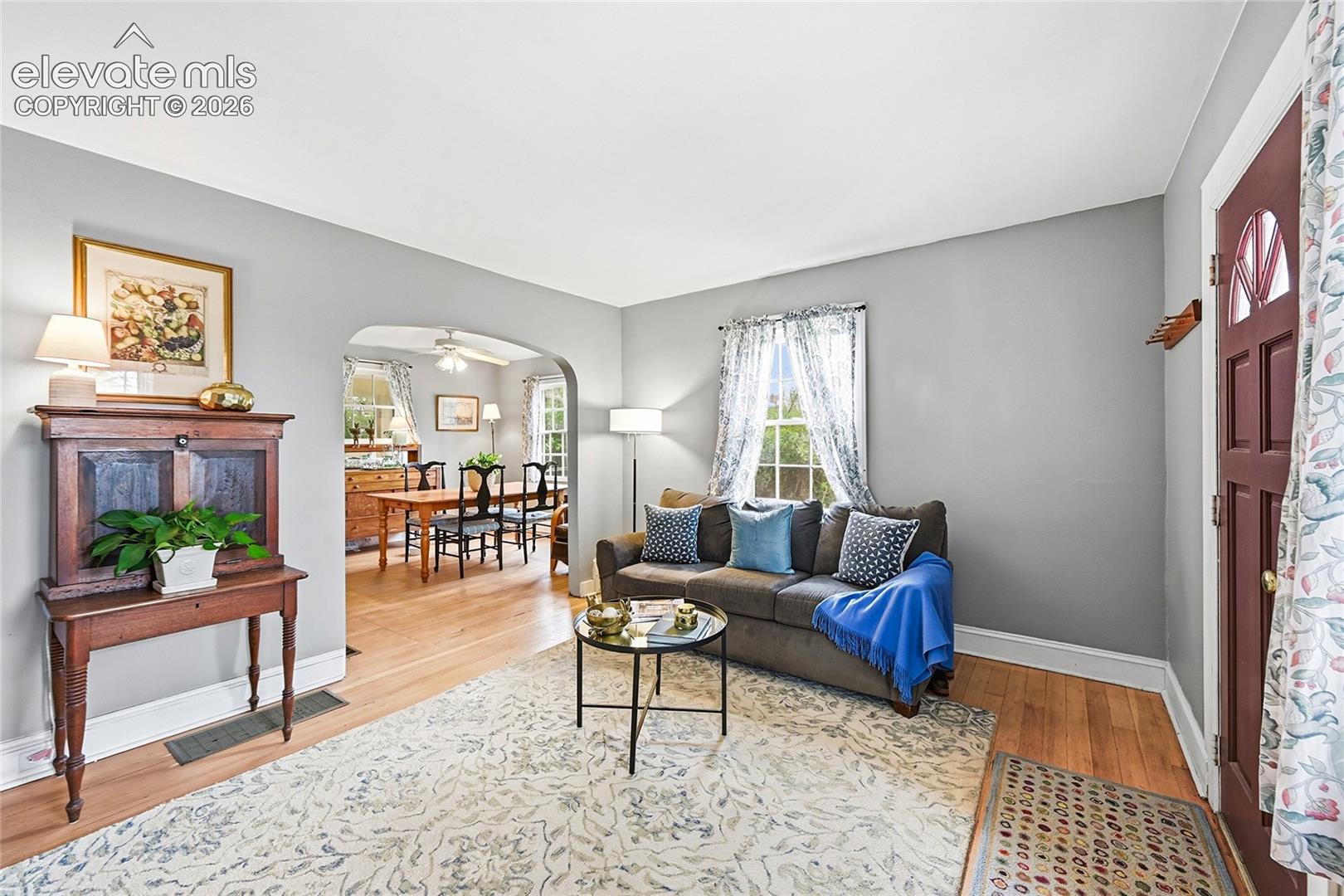 Living area featuring wood-finish flooring, an arched entryway, and a multi-pane entry door