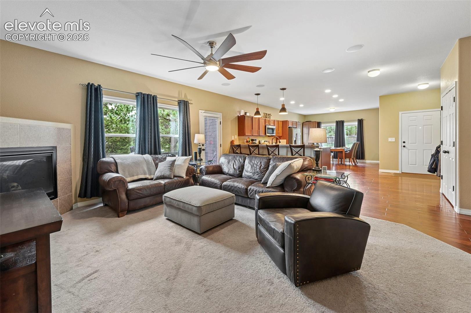 Spacious living area featuring a fireplace with a tiled surround, recessed lighting, and a ceiling fan