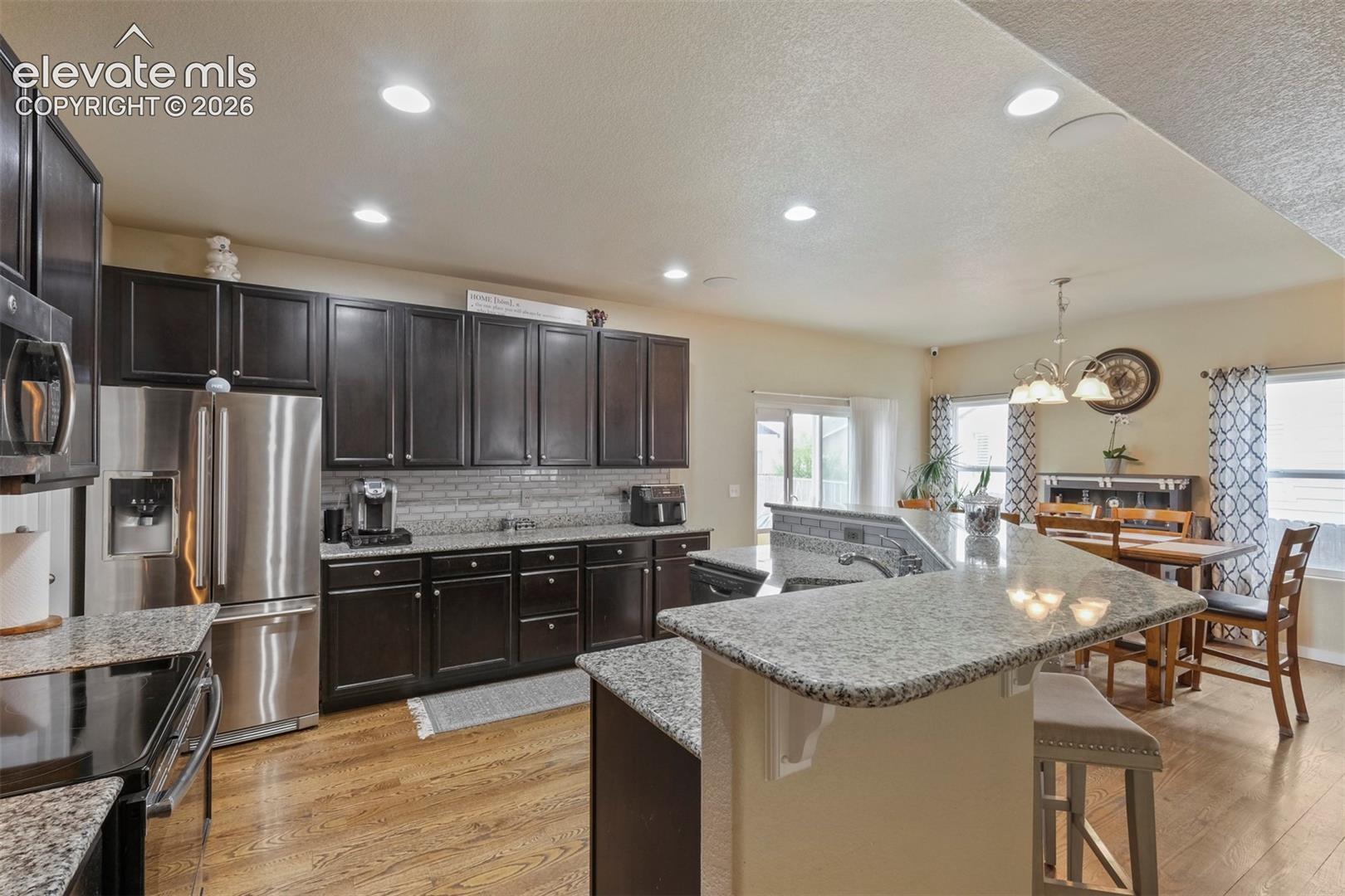 Kitchen featuring wood-finish flooring, dark wood cabinetry, and light-toned stone countertops