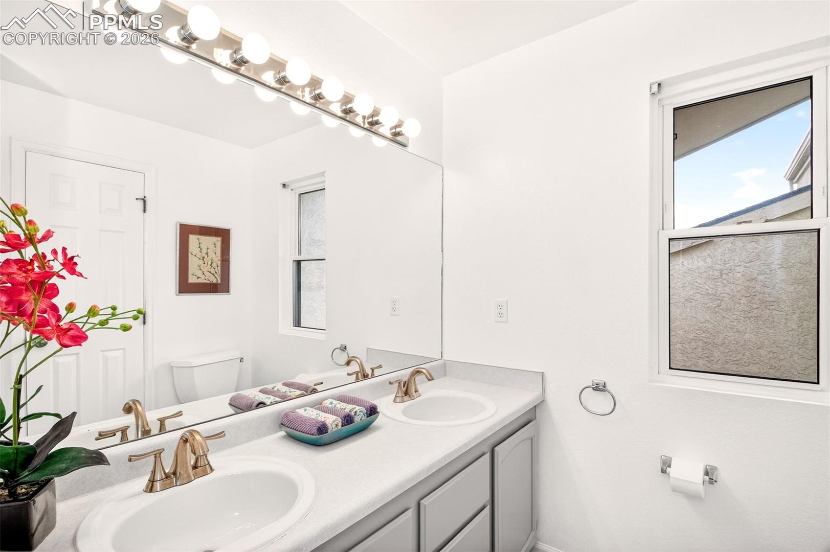 Primary ensuite with double sinks and a window offering natural light.