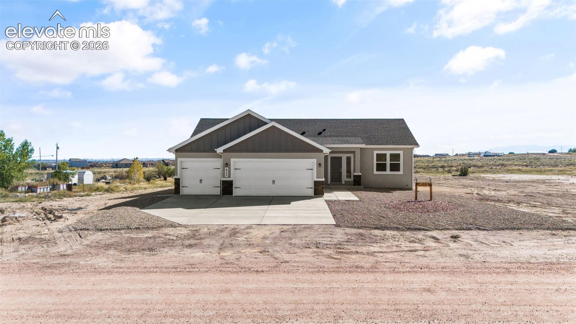 Single-story residence featuring a gray exterior with stone accents, a multi-gabled roofline, a three-car garage, and a concrete driveway