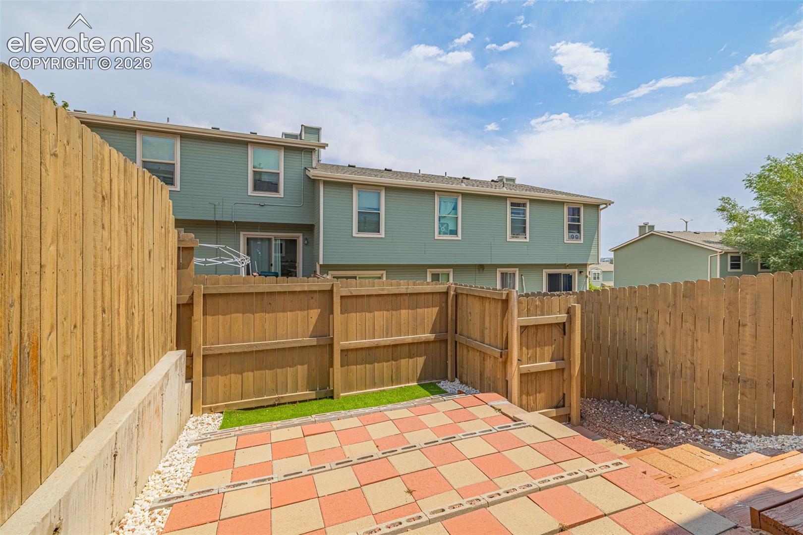 Private fenced yard with a tiled patio and artificial turf