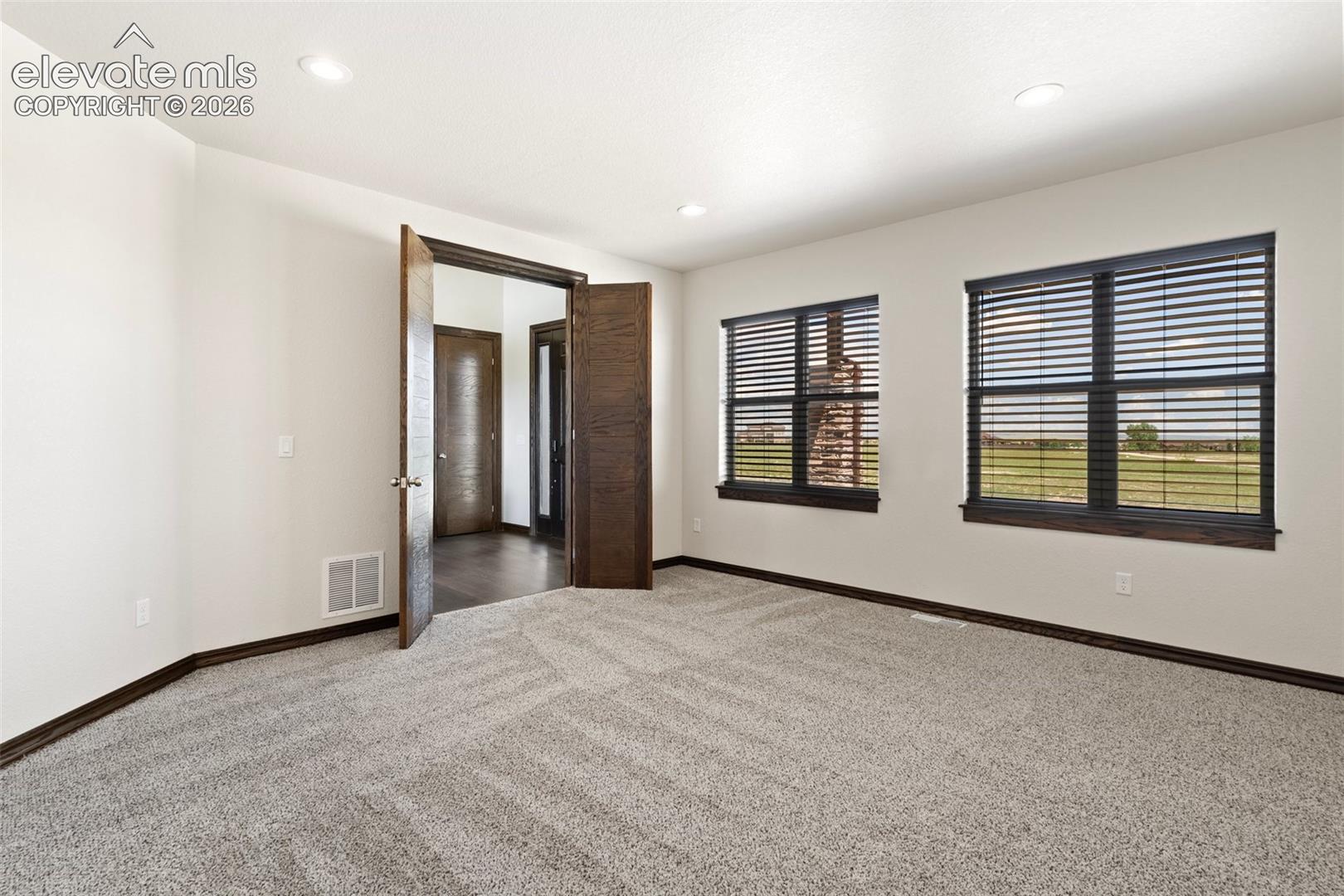 Spacious office featuring light-colored walls, recessed ceiling lighting, and patterned carpeting