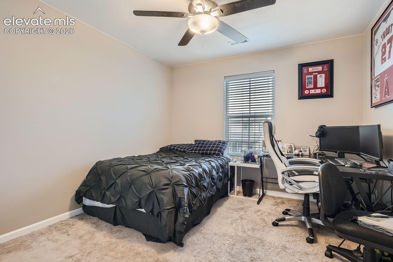 Neutral-toned interior space featuring neutral wall paint, wall-to-wall carpeting, a multi-blade ceiling fan with integrated lighting, and a window with horizontal blinds