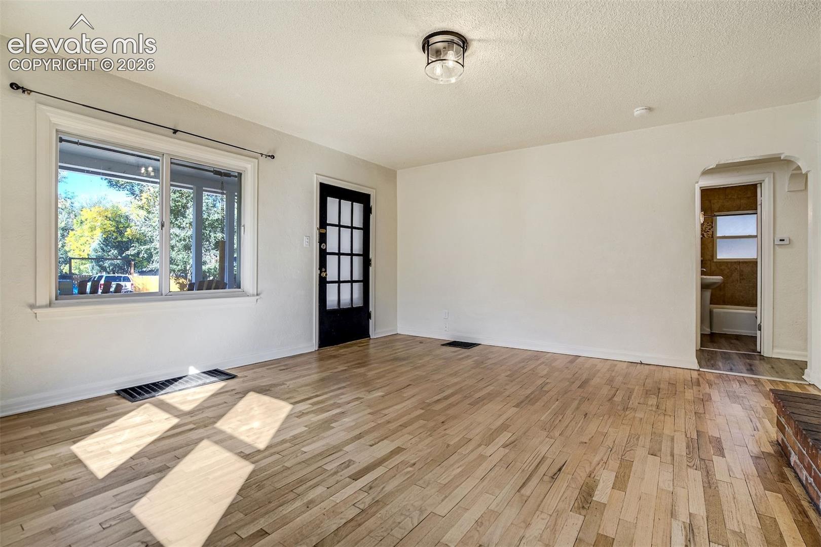 Interior space featuring wood-finish flooring, a multi-pane glass door, and an arched doorway entry