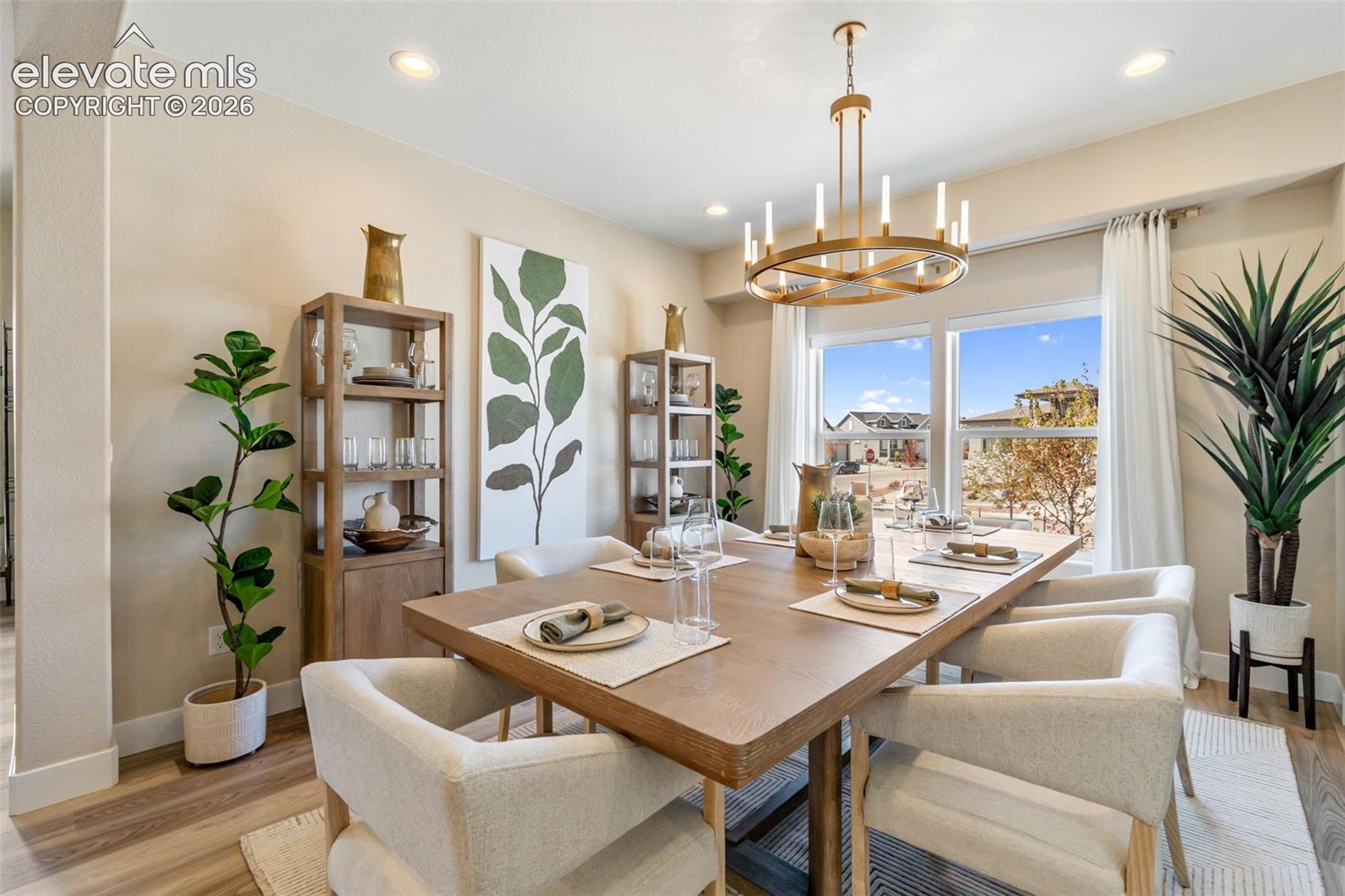 Dining area featuring wood-finish flooring, a contemporary circular metal chandelier, and large windows with natural light