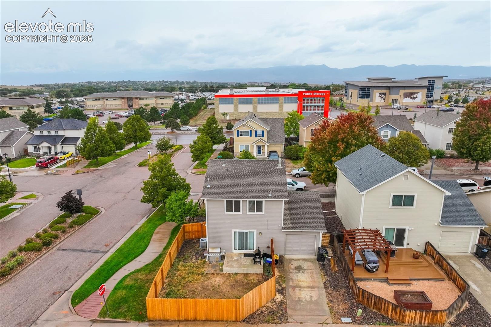 Gray siding exterior with attached garage, private fenced yard, and a rear deck with pergola