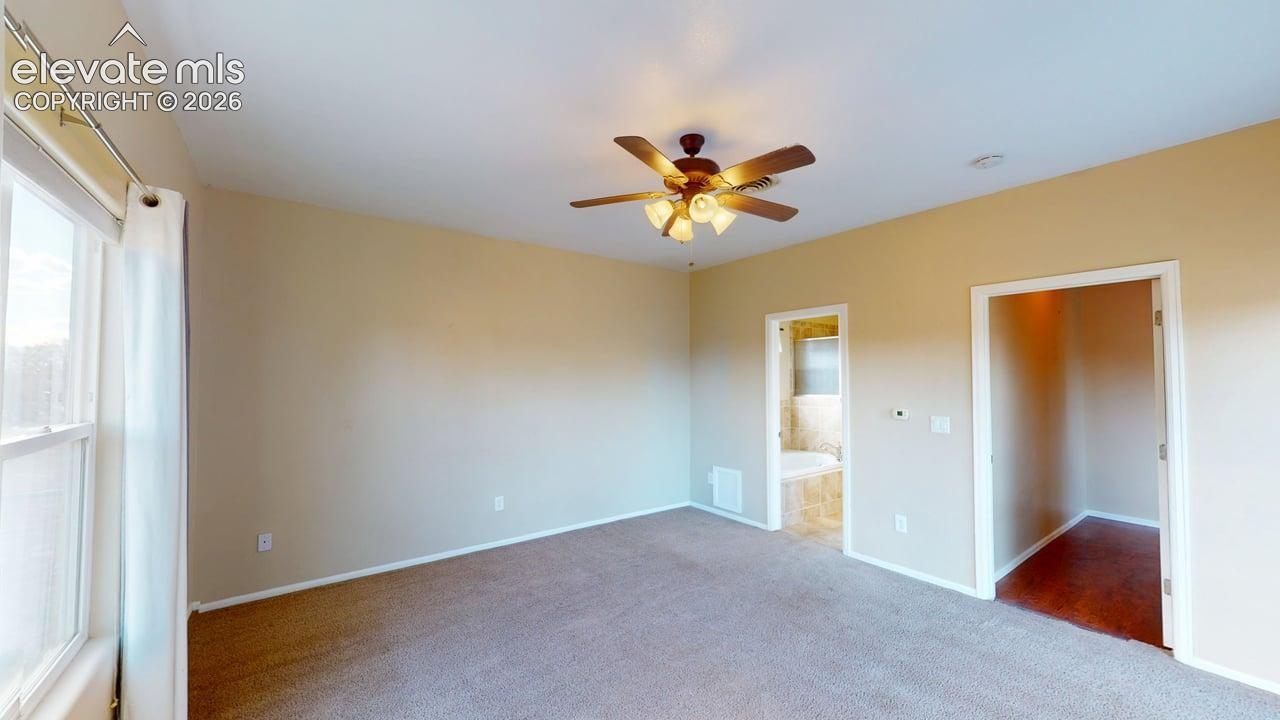 Carpeted room featuring a ceiling fan, window, and two doorways