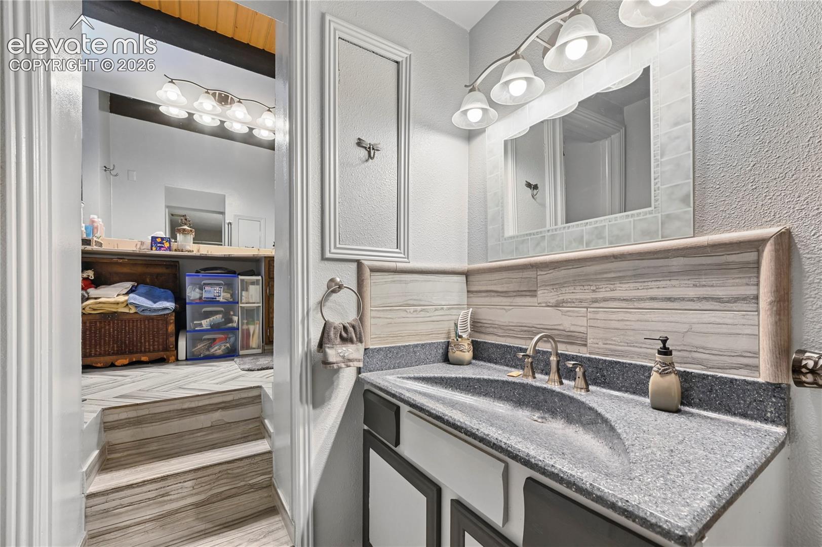 Vanity with integrated sink, brushed nickel faucet, and a tiled backsplash